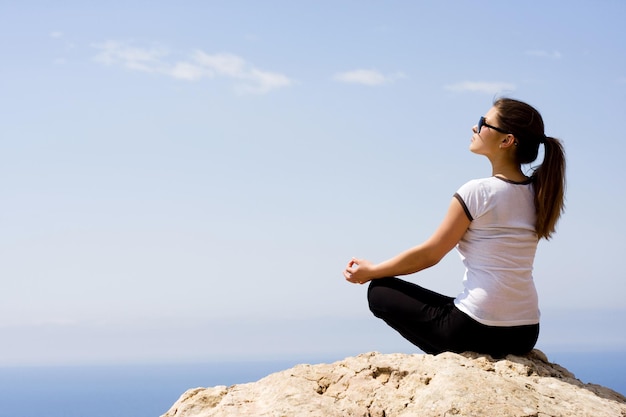 Young woman sitting on the rock near the sea