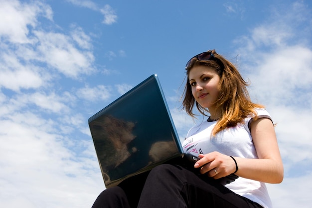 Young woman sitting on the rock with laptop