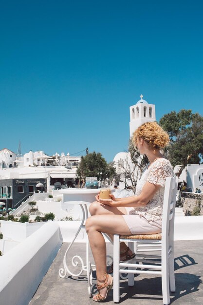 Young woman sitting on sofa against blue sky