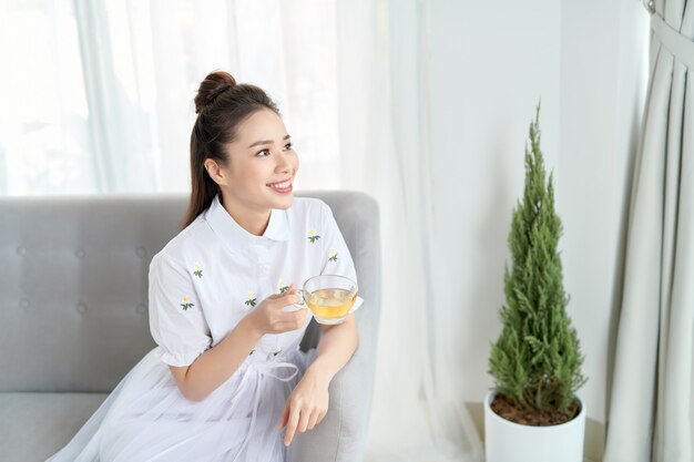 Young woman sitting in sofa and drinking tea.