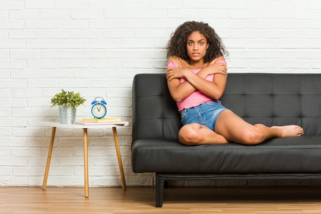 Young woman sitting on the sofa going cold due to low temperature or a sickness