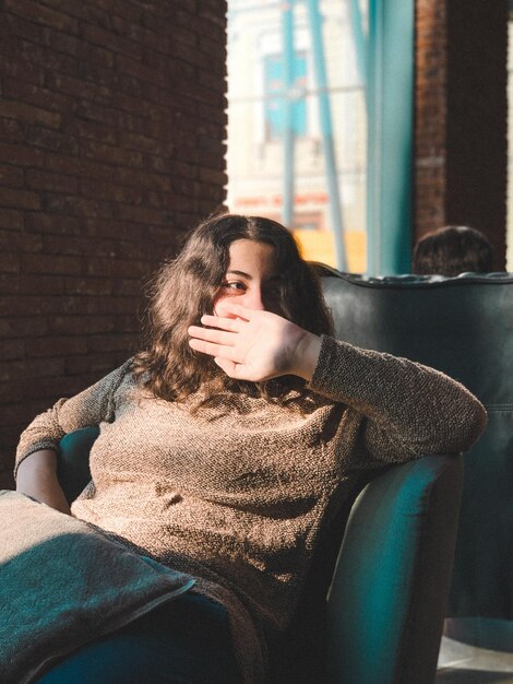 Photo young woman sitting on sofa at home