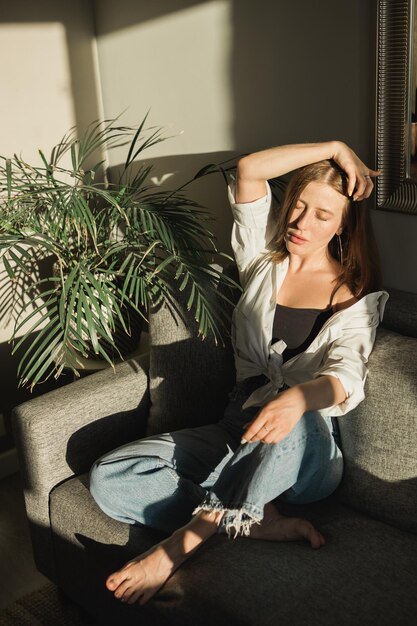 Photo young woman sitting on sofa at home