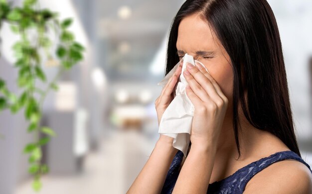 Young woman sitting on sofa with sneezing  running nose