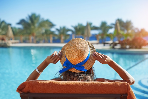 Young woman Sitting On Sun Lounger By Swimming Pool