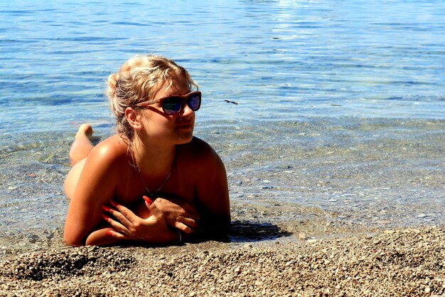 Young woman sitting on sunglasses at beach