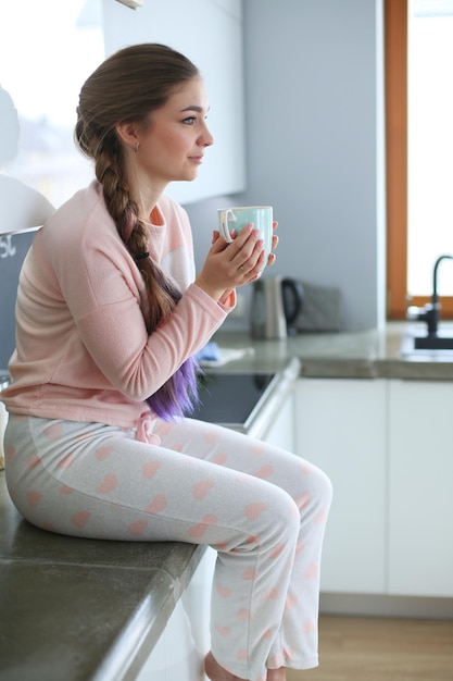 Young woman sitting on table in the kitchen