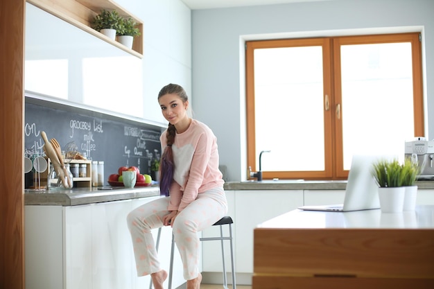 Young woman sitting on table in the kitchen