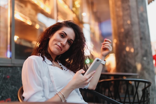 Young woman sitting at a table on the street in the evening. High quality photo