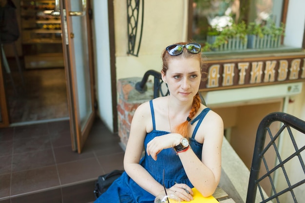 young woman sitting on the terrace in a cafe writing down her plans