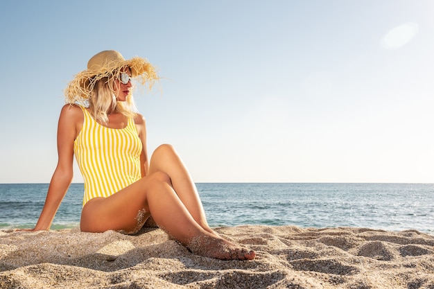 Giovane donna seduta su una spiaggia tropicale.