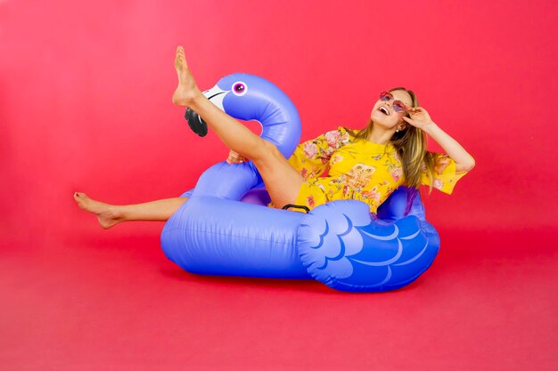 Young woman sitting with toy against red background