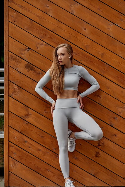 Young woman sitting on wooden wall