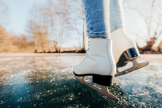 Молодая женщина катается на коньках на открытом воздухе на пруду в морозный зимний день