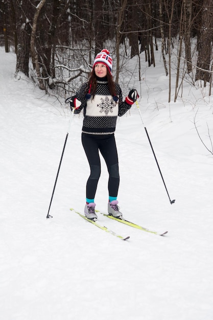 Young woman skiing in the park White winter forest and skier