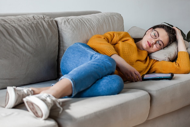 Photo young woman sleep on sofa using mobile phone