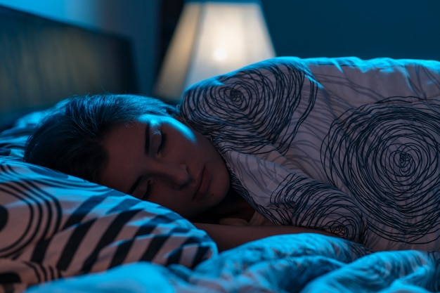 Young woman sleeping in a bed in a dark bedroom