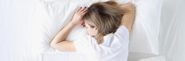 Giovane donna che dorme a pancia in giù nel letto bianco vista dall'alto concetto di sonno sano