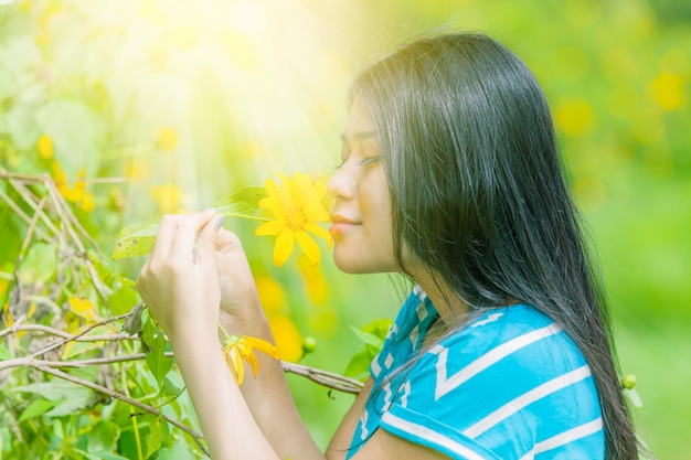 Young woman smelling flowers in the flower garden