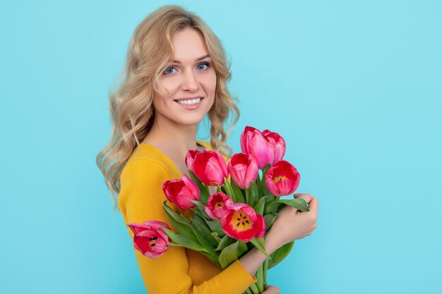 3월 8일 파란색 배경에 봄 튤립 꽃을 들고 웃는 젊은 여성