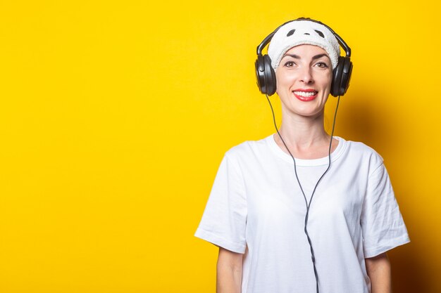 Photo young woman smiles in a sleep mask and headphones, listens to music .