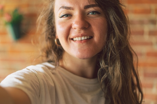 Фото Молодая женщина улыбается и смотрит в камеру и принимает концепцию образа жизни селфи