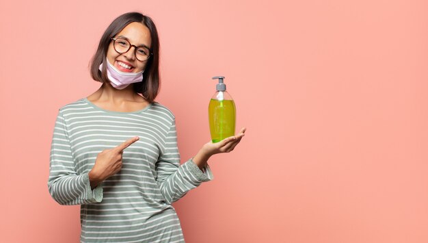 Young woman smiling cheerfully, feeling happy and pointing to the side and upwards, showing object in copy space