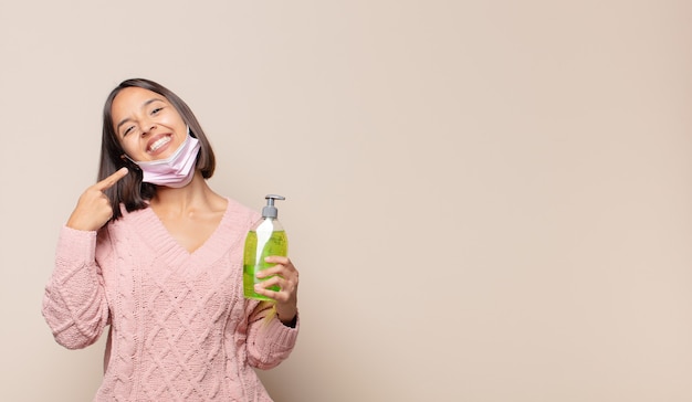 Young woman smiling confidently pointing to own broad smile, positive, relaxed, satisfied attitude