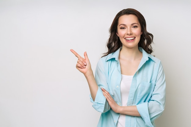 Young woman smiling and gesturing to copy space.