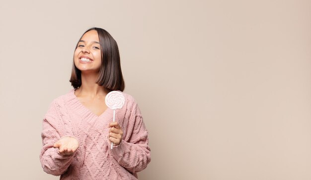 Young woman smiling happily with friendly, confident, positive look, offering and showing an object or concept