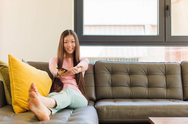 Young woman smiling happily with friendly, confident