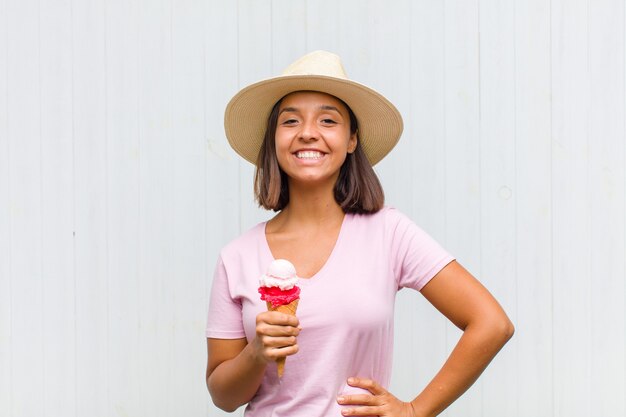 Young woman smiling happily with a hand on hip and confident