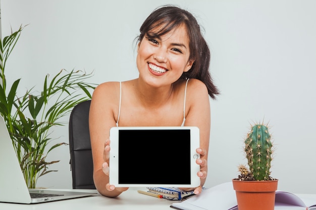 young woman smiling and holding a tablet