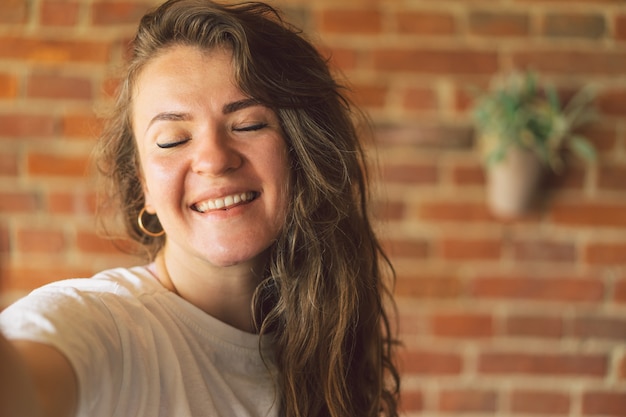 Foto giovane donna che sorride e guarda a porte chiuse e prende un concetto di stile di vita selfie