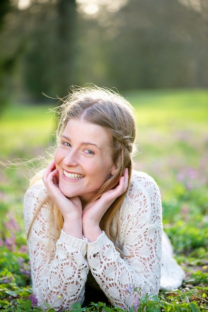 Young woman smiling lying on grass and flowers