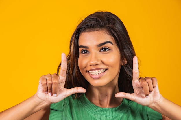 Young woman smiling making photo frame with hands and fingers with a happy face. creativity and photography concept.