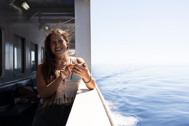 Foto giovane donna sorridente e parlando al telefono in un traghetto