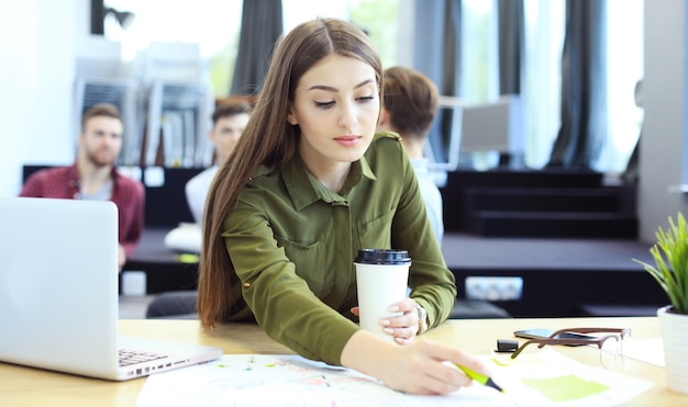 Young woman smiling and typing on laptop in modern office.