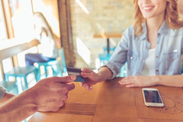 Photo young woman smiling while giving a credit card.