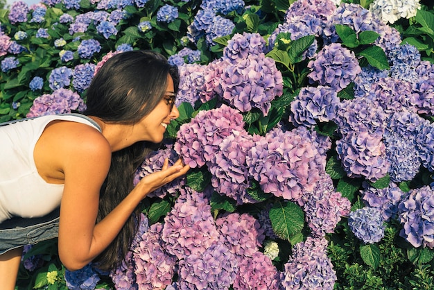 Foto giovane donna che sorride mentre odora i fiori