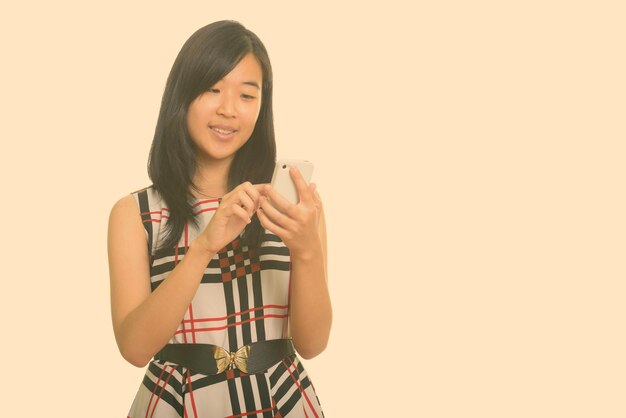 Young woman smiling while standing against gray background