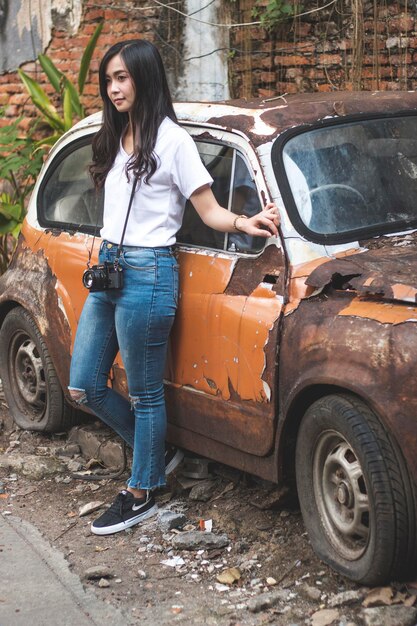 Photo young woman smiling while standing by abandoned car