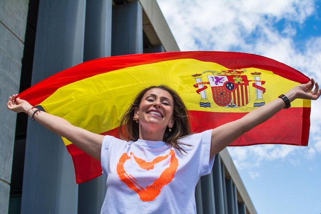 Foto giovane donna sorridente con la bandiera spagnola. felice giovane adulto che sventola una bandiera.