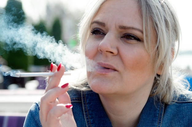 Young woman smoke cigarette and blow smoke from mouth