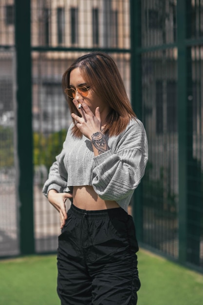 Young woman smoking a cigarette in a green playground