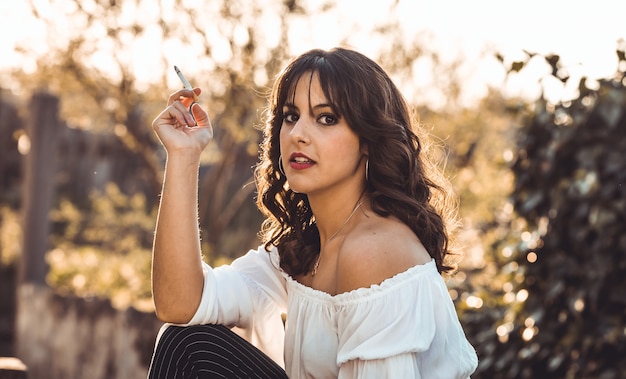 Young woman smoking outdoor at sunset