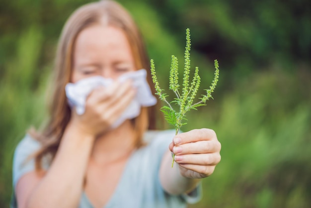 Foto la giovane donna starnutisce a causa di un'allergia all'ambrosia