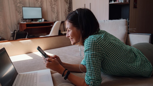 Young woman on sofa happily working on new project with laptop in home