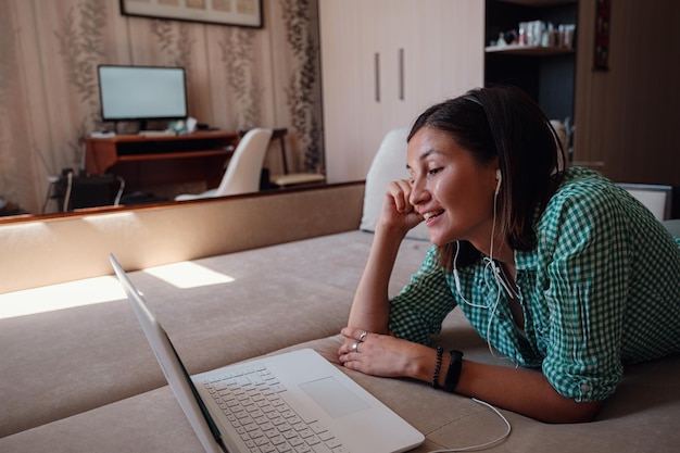 Photo young woman on sofa happily working on new project with laptop in home