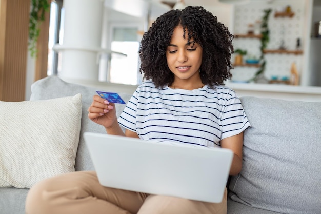 Giovane donna sul divano shopping online con carta di debito bella ragazza utilizzando il computer portatile per lo shopping online a casa